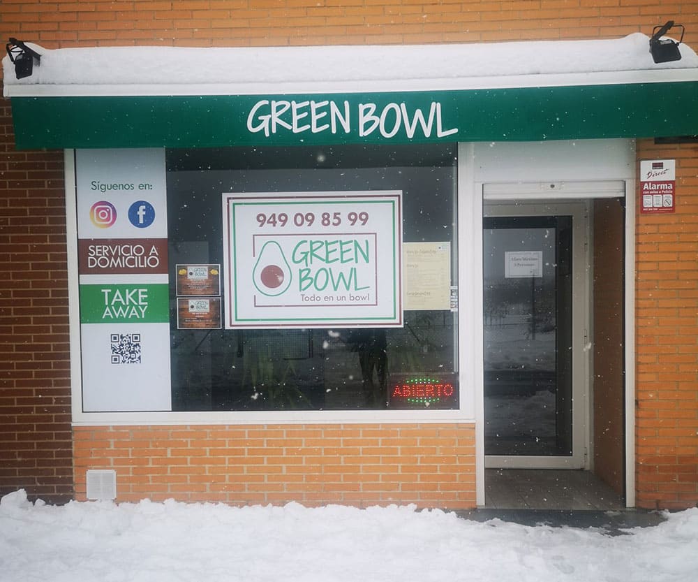 Fotografía de la fachada del local de Green Bowl con nieve en el suelo.